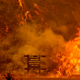A sign warning people about Covid-19 is surrounded by flames during the Hennessey Fire near Lake Berryessa in Napa, California on Aug. 18, 2020.